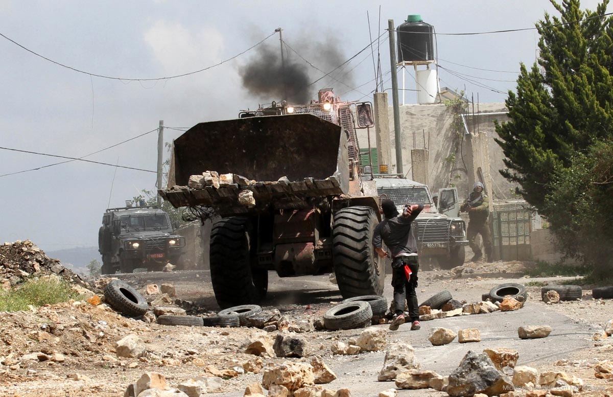 Un manifestante palestino arroja piedras contra un bulldozer israelí en Nablús, Cisjordania.