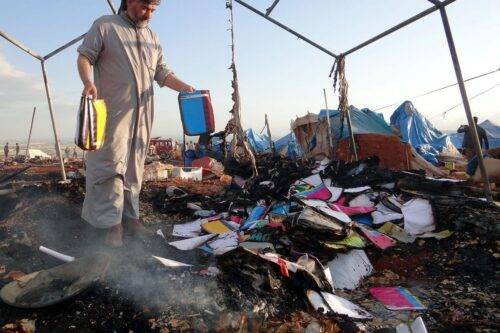 Personal inspecciona los daños materiales después de que un caza sirio bombardease el campo de refugiados de Karmuna, cerca de la ciudad siria de Idlib, en donde murieron 8 personas y 30 resultron heridas el 5 de Mayo de 2016. Imagen de Agencia Anadolu.