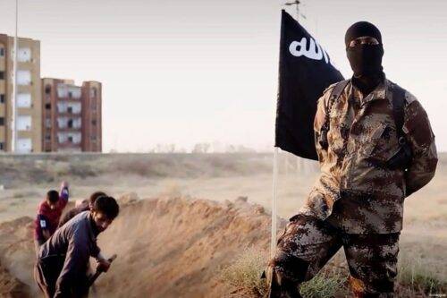 Un combatiente del ISIS frente a un grupo de prisioneros que cavan sus propias tumbas.