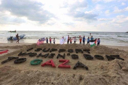 Varios niños se reúnen frenta a una escultura de arena mostrando su apoyo al Barco de Mujeres Rumbo a Gaza de 2016. (Flickr/rumboagaza)