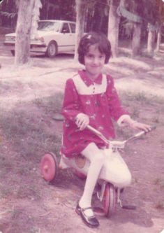 Raya, en Irak, montando un triciclo en su infancia