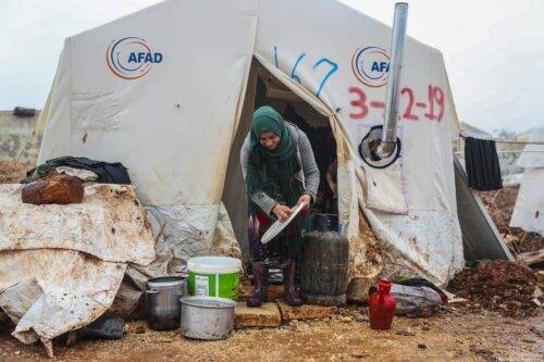 Se ve a una mujer siria frente a su tienda de campaña en un campamento donde se alojan familias sirias, que se han visto obligadas a desplazarse debido a los ataques llevados a cabo por el régimen de Assad y Rusia, en Idlib, Siria, el 10 de enero de 2020 [Agencia Esra Hacioğlu / Anadolu]