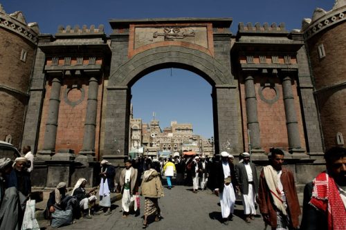 Los yemeníes caminan bajo la emblemática Puerta de Yemen que conduce a la antigua ciudad de Sanaa el 8 de noviembre de 2009 [MARWAN NAAMANI/AFP vía Getty Images]